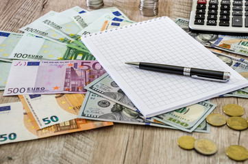 Euro, dollars, coins, notebook, pen and calculator on wooden background close up