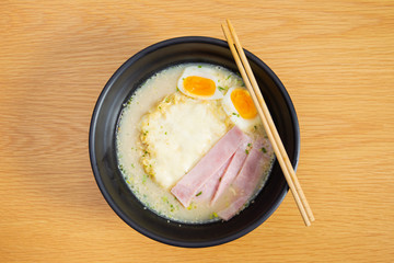 Traditional pork soup Japanese raman with boiled egg and ham in black ceramic bowl close up.