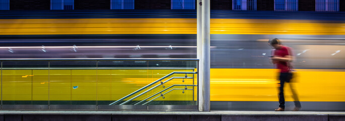 Pepople in a trainstation with motion blurred trains moving fast (color toned image)