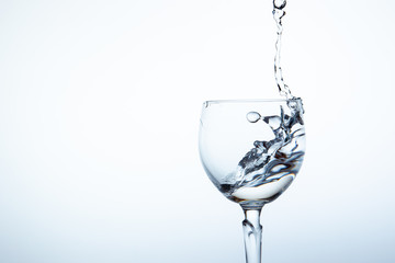 Water splashing in the luxury wine glass close up.  Concept of good healthy and refreshment.  Copy space on left side on the image.