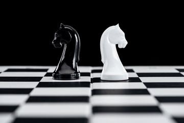 selective focus of chessboard and white and black knights isolated on black