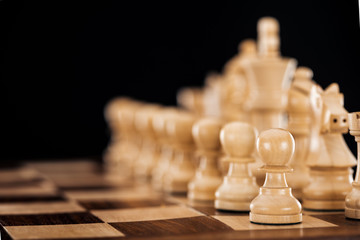 selective focus of beige and brown wooden chessboard with chess figures isolated on black