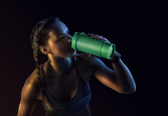 Young muscular build woman silhouette drinking water of bottle. Attractive athlete resting after...