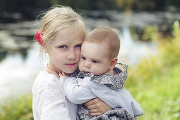 Fototapeta premium Happy sisters. Children girls outdoor (1 and 8 eyears old)