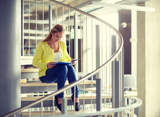 education, high school, university, learning and people concept - smiling student girl reading book sitting on stairs