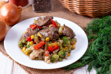 Chicken liver with vegetables in a plate on a table