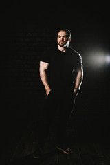 Young handsome sportsman bodybuilder weightlifter with an ideal body, after coaching poses in front of the camera. In sportswear.