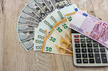 dollars, euro and and calculator on wooden background