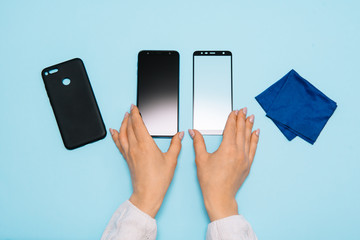 Smartphone with screen protect glass cover in hands. blue background. women hand stick tempered glass shield or film screen cover with mobile phone. protector concepts ideas