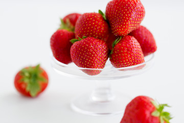 fruit, food and berries concept - strawberries on glass stand over white background