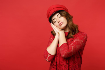 Relaxed young woman in lace dress, cap keeping eyes closed, sleeping with hands near face isolated on bright red background in studio. People sincere emotions, lifestyle concept. Mock up copy space.