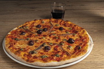 pizza pomodoro acciughe capperi olive nere intera nel piatto