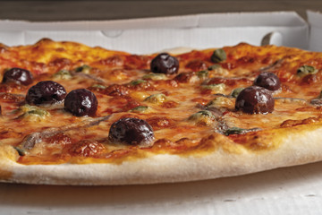 pizza pomodoro acciughe capperi olive nere intera nella scatola dal basso primo piano