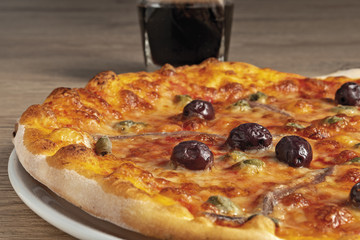 pizza pomodoro acciughe capperi olive nere intera nel piatto dal basso primo piano vista sinistra