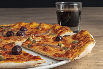 pizza pomodoro acciughe capperi olive nere tagliata nel piatto dal basso primo piano vista destra