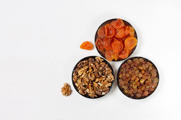 Dried apricot, raisins, walnut in saucers,on a white background.