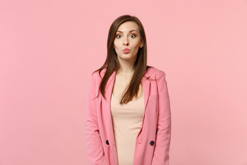 Side view of cheerful funny pretty young woman in jacket looking camera, blowing lips isolated on pastel pink wall background in studio. People sincere emotions, lifestyle concept. Mock up copy space.