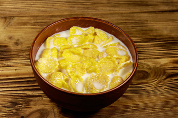 Cornflakes with milk in a bowl on wooden table