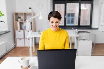 business, technology and people concept - smiling businesswoman with laptop computer working at office