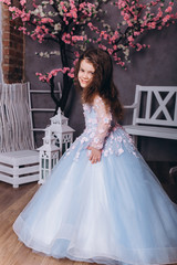 Cute adorable baby girl in elegant blue wedding dress indoors posing and looking at camera. Childhood, fashion kids concept