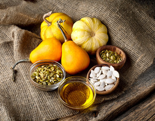 Pumpkin, pumpkin seeds and oil on wooden background