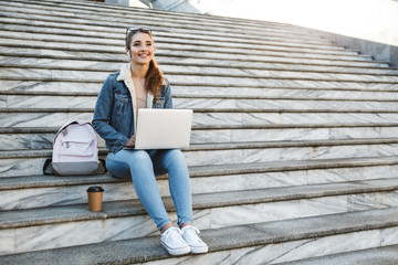 Smiling young woman wearing jacket sitting on a bench