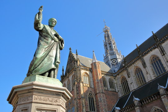 The statue of Laurens Janszoon Coster (erected in 1722) with the ornate and colorful architecture of St Bavokerk Church in the background, Haarlem, Netherlands