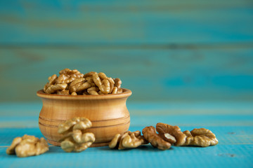 Walnuts on blue rustic table in wooden bowl