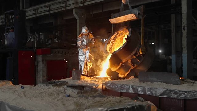 Man working with liquid metal in factory. Metal factory sparks