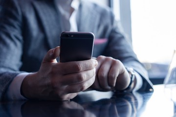 Business man holding smartphone, using application to booking suite in hotel for business trip, using wireless connection to internet, resting in cafe, drinking coffee.
