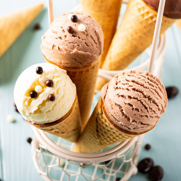 Homemade coffee, vanilla and chocolate ice cream in waffle cones on turquoise background. Healthy summer food concept.