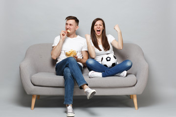 Couple woman man football fans cheer up support favorite team with soccer ball, holding bowl of...