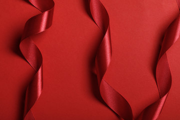 close up of curved silk red ribbons on red background