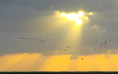 Sunlight pierces through the clouds as sun rises over a lake