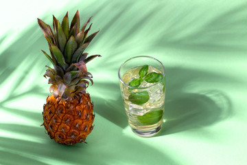 Pineapple juice with palm leaves on green