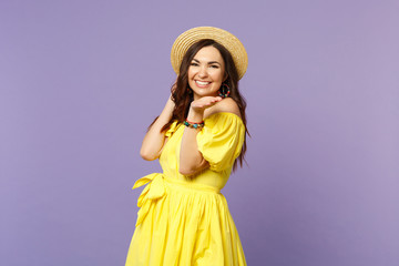 Portrait of smiling young woman in yellow dress, summer hat looking, pointing hand on camera isolated on pastel violet wall background. People sincere emotions, lifestyle concept. Mock up copy space.