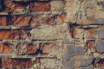 Red brick wall in the cracks. Shattered brick wall close up. Old ruined brick wall. Dilapidated brick wall. Urban texture.   Grunge texture brick wall background.