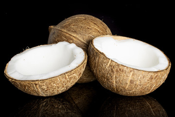 Group of one whole two halves of fresh bio coconut isolated on black glass
