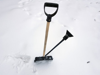 Snow shovel and ice ax stuck in the snow in winter