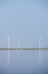 wind turbines and blue sky reflected in water of eemmeer near huizen in holland