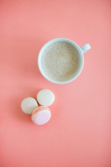 Cup of fresh coffee with macaron on living coral background