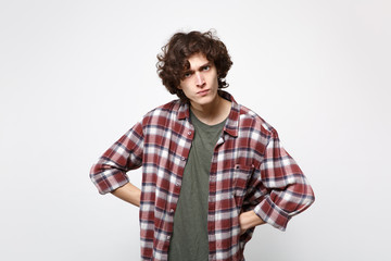 Portrait of angry strict young man in casual clothes standing with arms akimbo on waist isolated on white wall background in studio. People sincere emotions, lifestyle concept. Mock up copy space.