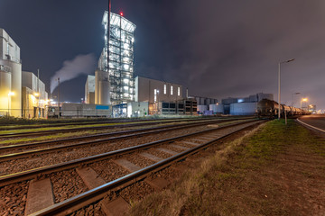 Fototapeta premium Night view of an industrial zone with the rail road transporting in and out raw material