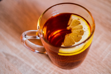 Healthy glass of hot tea with a lemon slice isolated on a wood table