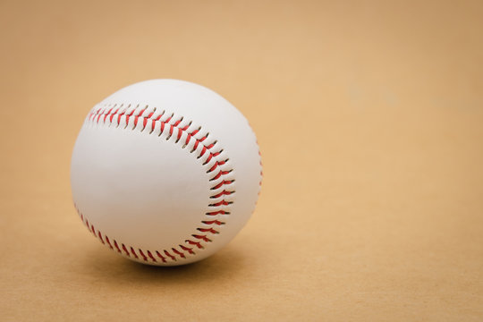 Isolated baseball on a brown background and red stitching baseball. White baseball with red thread.Baseball is a national sport of Japan. It is popular.