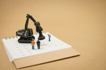 Miniature people Construction worker repair with white calendar using as background business concept and Manage schedules concept with copy space  for your text or design.
