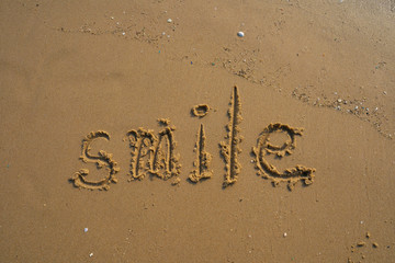 Vacation on the sand beach concept. Smile words written into the sand on the beach at Rayong, Thailand