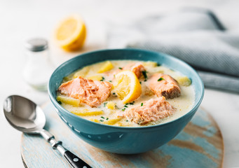 Close up of soup with salmon, cream and potatoes in a blue bowl