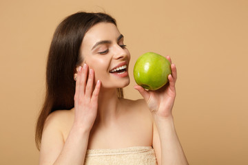 Close up brunette half naked woman 20s with perfect skin, nude make up hold apple isolated on beige pastel wall background, studio portrait. Healthcare cosmetic procedures concept. Mock up copy space.