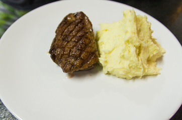 Duck breast with orange sauce on plate decorated with flowers.